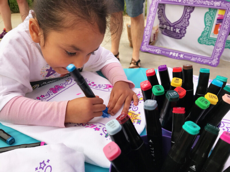 Young girl decorating Pre-K Priority t-shirt