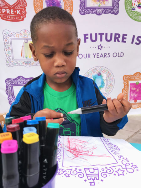 Young boy with marker, decorating Pre-K Priority t-shirt