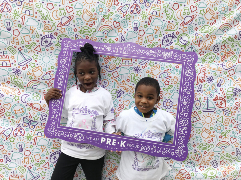 Two young children posing with Pre-K Priority selfie frame