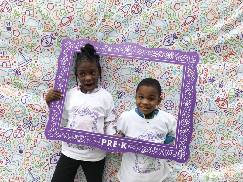 Two young children posing with Pre-K Priority selfie frame